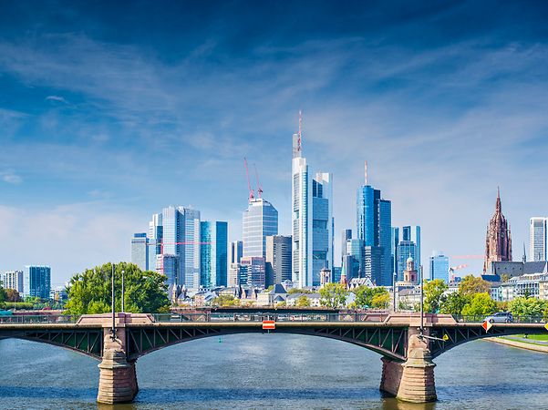 Stadtansicht mit moderner Skyline und Brücke über einen Fluss.
