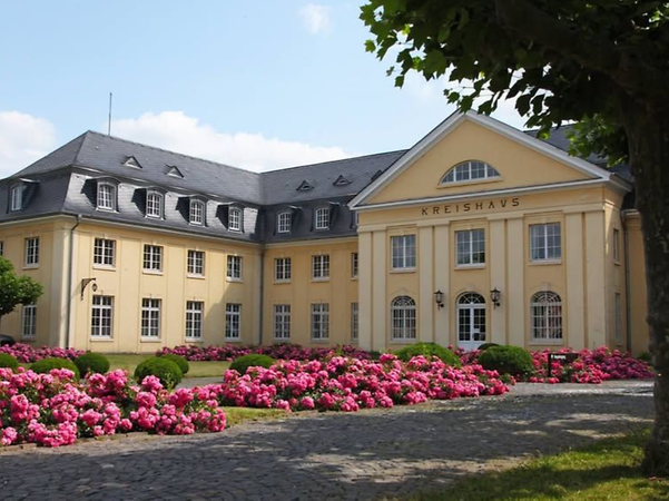 Verwaltungsgebäude der Kreisverwaltung Bernkastel-Wittlich mit Blumenbeeten im Vordergrund.