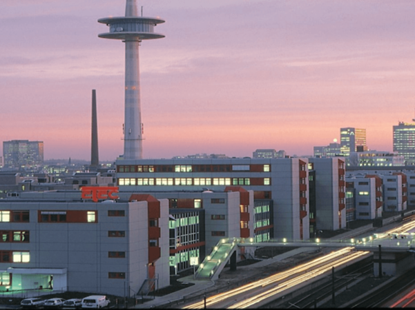 Stadtansicht von Essen mit modernen Gebäuden, Straßenverkehr und markantem Fernsehturm bei Dämmerung.