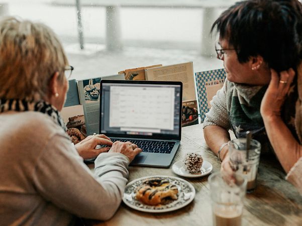 Zwei Personen arbeiten gemeinsam am Laptop am Tisch