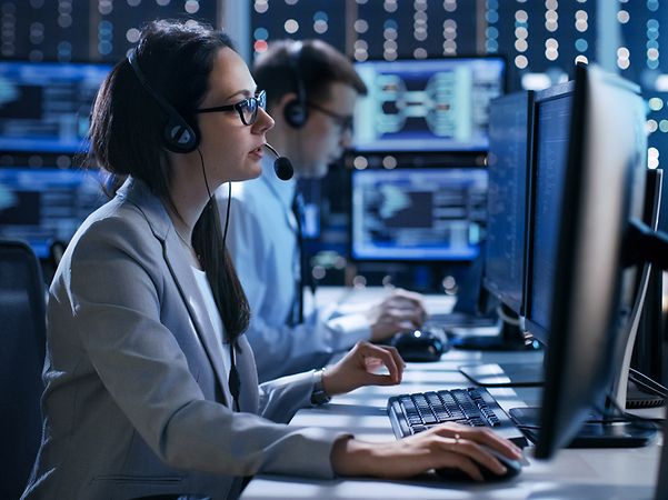 Person arbeitet an mehreren Monitoren im Leitstellenumfeld