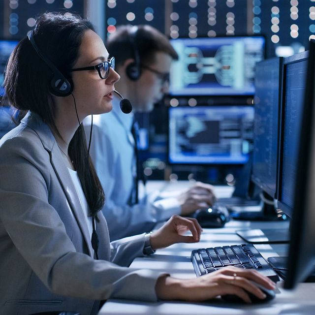 Zwei Mitarbeitende sitzen im Büro mit Headset und nutzen AlarmRuf der Telekom