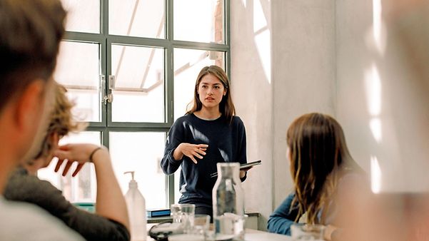 Frau steht im Meeting-Raum und berät Menschen zu SAP S/4HANA®.