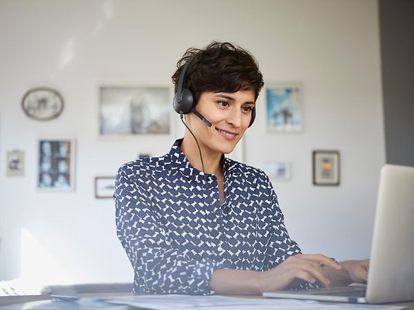 Telekom-Mitarbeiterin berät Kundin oder Kunde via Telefonat am Computer.