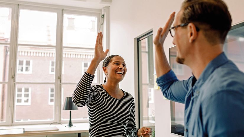 Zwei Menschen geben sich nach einem erfolgreichen Projekt im Büro ein High Five.
