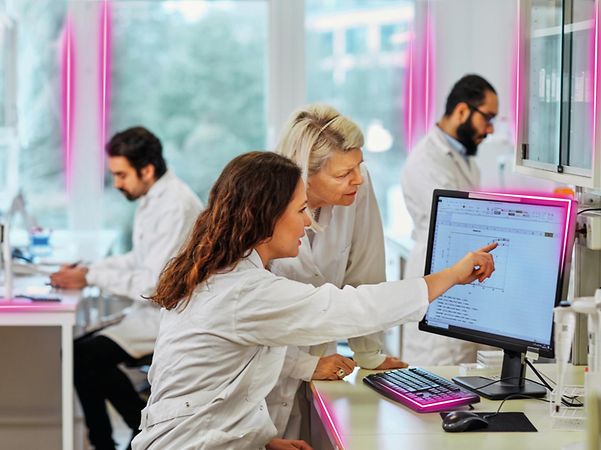 Forschende im Labor betrachten gemeinsam ein Diagramm auf einem Monitor.