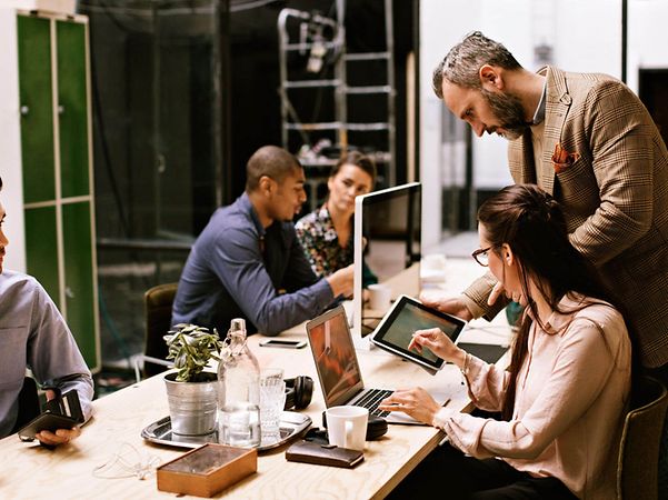 Mehrere Personen arbeiten gemeinsam in großem Büro dank Vernetzung, Internet und Cloud der Telekom