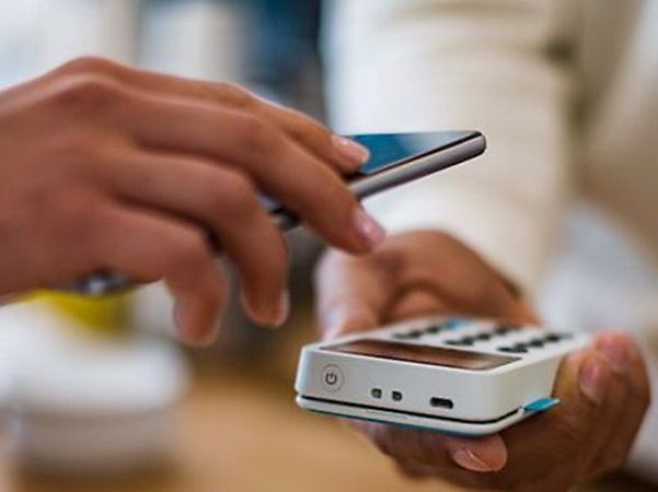 Person bezahlt kontaktlos mit einem Smartphone an einem Kartenlesegerät.