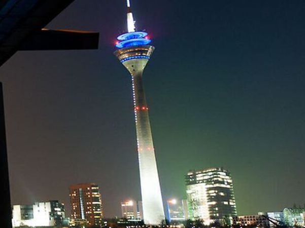 Beleuchteter Rheinturm in Düsseldorf mit moderner Skyline bei Nacht.