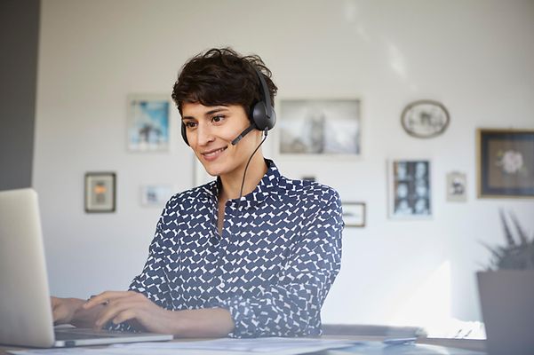 Telekom-Mitarbeiterin berät Kundin oder Kunde via Telefonat am Computer.